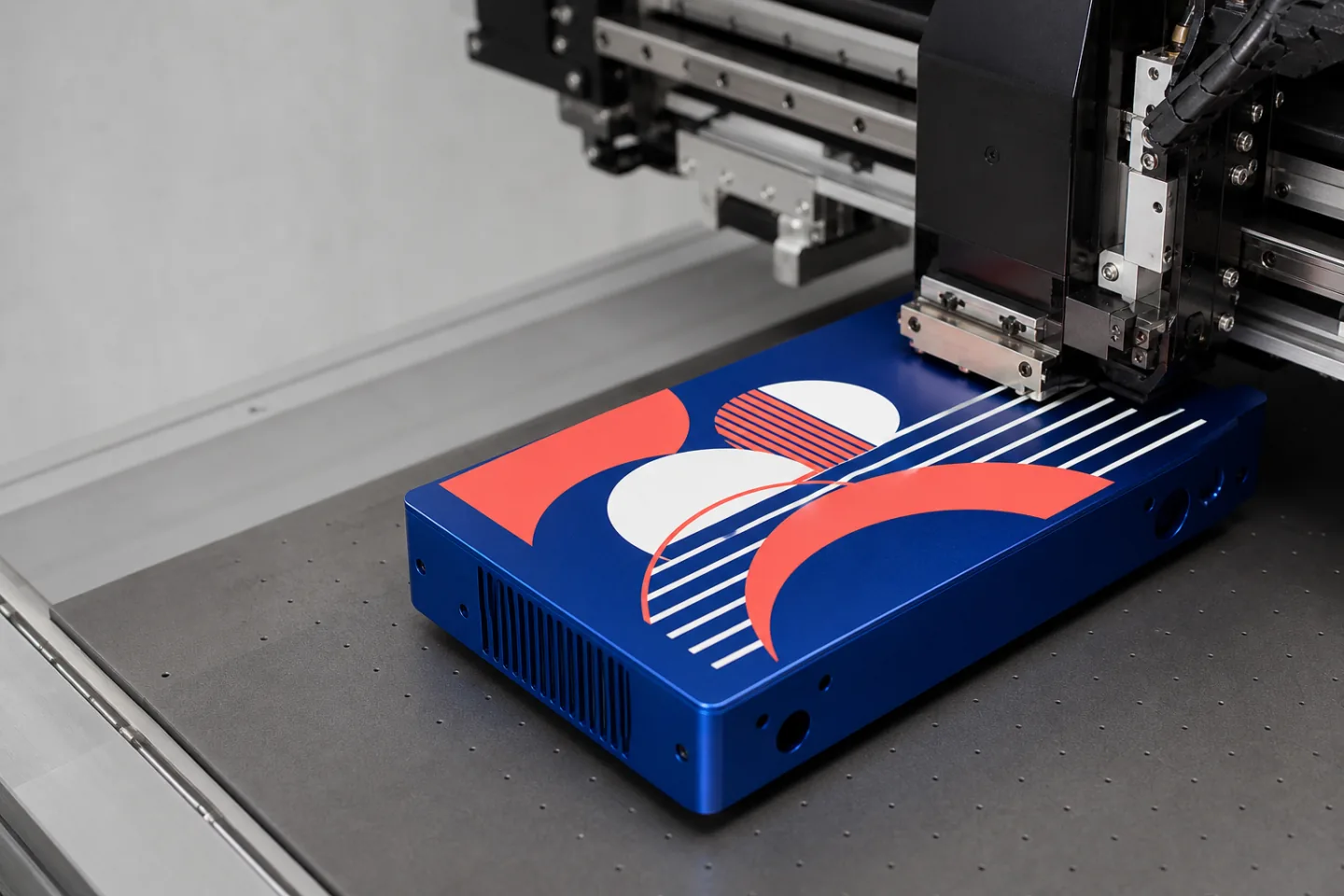 UV printer applying coral and white graphics to a blue metal enclosure